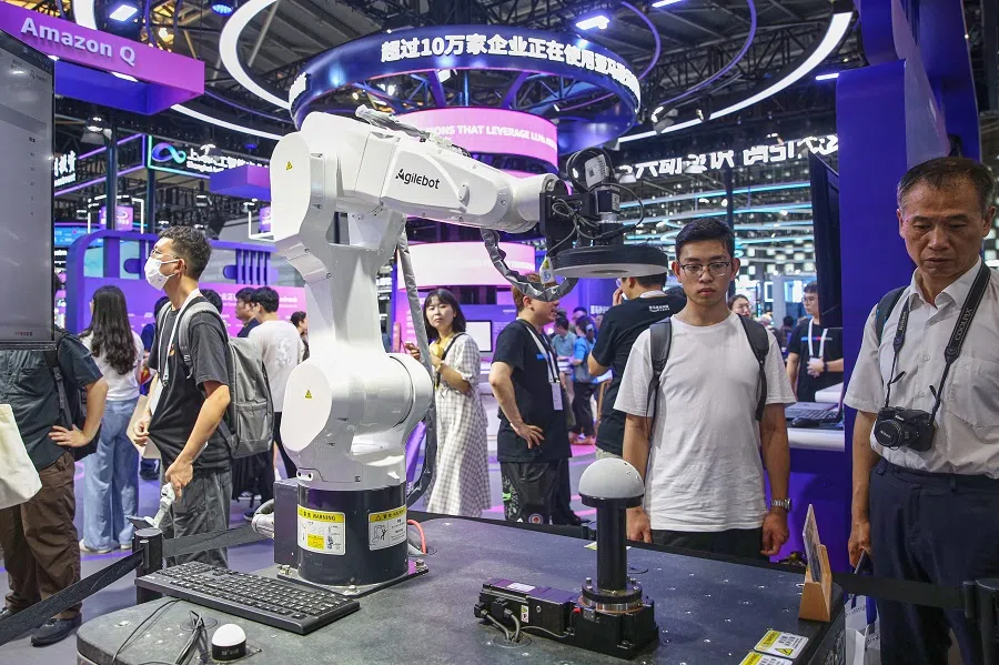 Visitors look at a robot arm by Agilebot during the World Artificial Intelligence Conference (WAIC) in Shanghai on 5 July 2024.  (AFP)