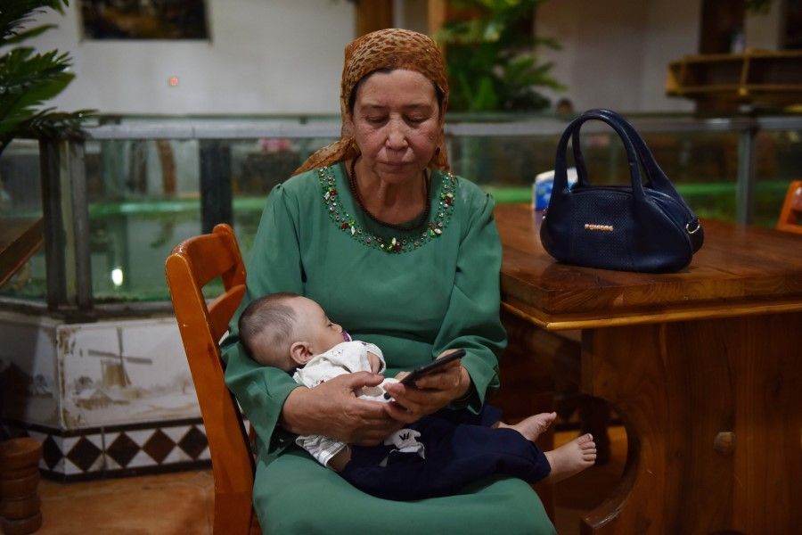 This file photo taken on 31 May 2019 shows a Uighur woman holding a baby in a Uighur restaurant in Hotan in China's northwest Xinjiang region. Chinese authorities are carrying out forced sterilisations of women in an apparent campaign to curb the growth of ethnic minority populations in the western Xinjiang region. (Greg Baker/AFP)
