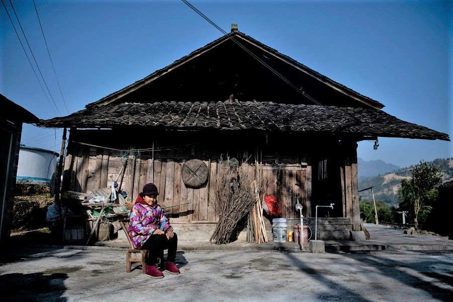 This picture taken on 12 January 2021 shows a woman sitting in front of her residence in Baojing County, Hunan province, China. (Noel Celis/AFP)