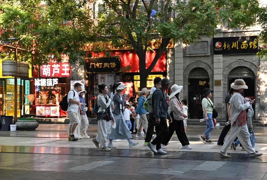 People walk around the Qianmen promenade in Beijing on 21 June 2025. (Adek Berry/AFP)