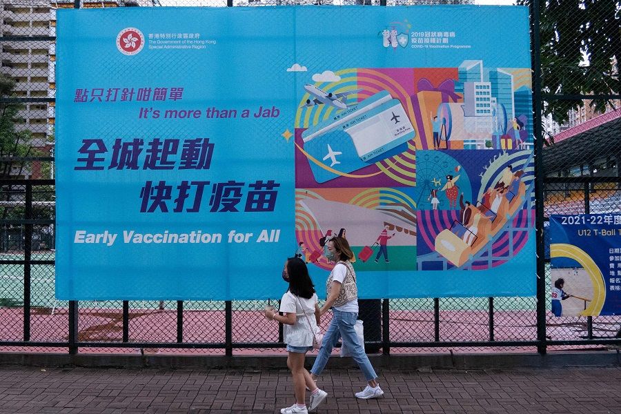 People walk past a government banner encouraging the public to take the Covid-19 vaccine in Hong Kong on 15 August 2021. (Bertha Wang/AFP)