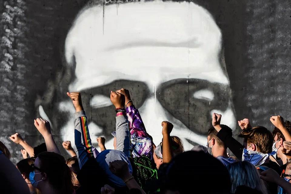 People raise their hands as they protest at the makeshift memorial in honour of George Floyd, on 4 June 2020, in Minneapolis, Minnesota. (Chandan Khanna/AFP)