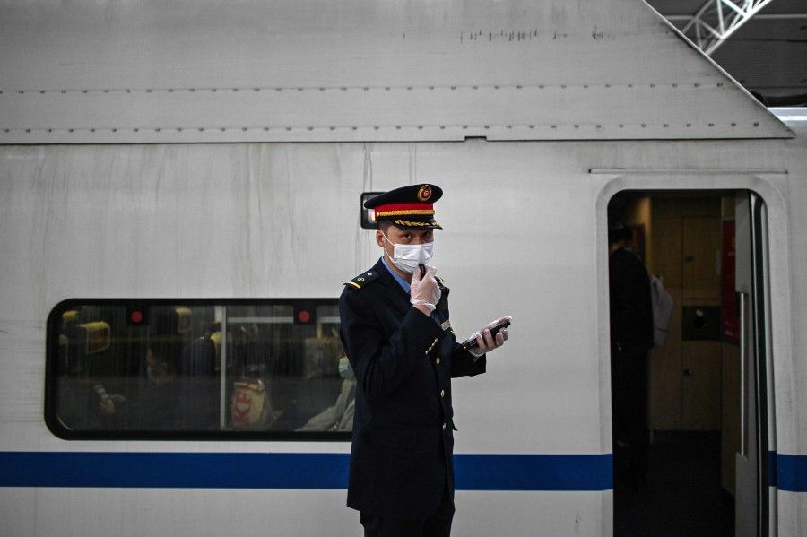 A train station employee is seen at the Shanghai railway station on 23 March 2021. (Hector Retamal/AFP)