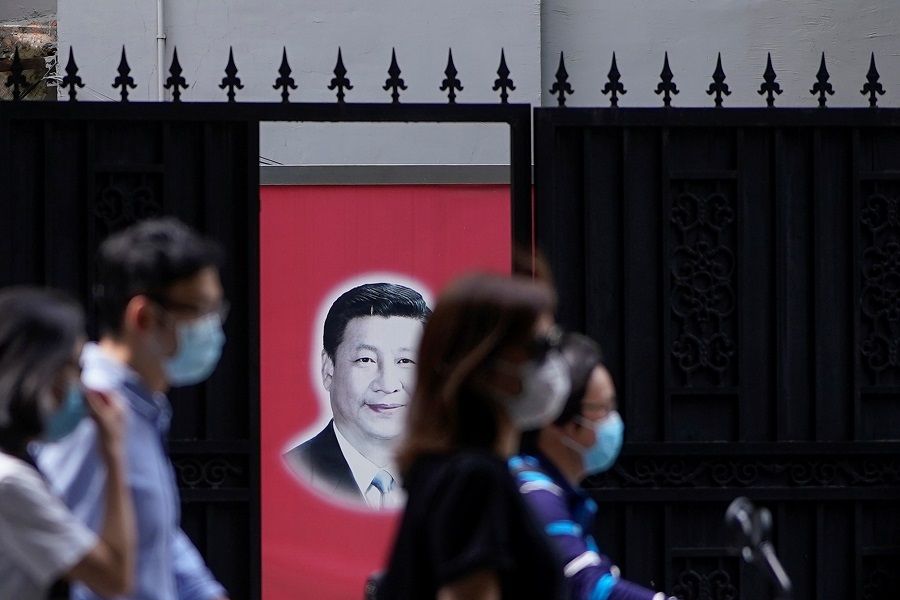 People wearing masks are seen in front of a portrait of Chinese President Xi Jinping on a street on the opening day of the National People's Congress, in China, on 22 May 2020. (Aly Song/Reuters)