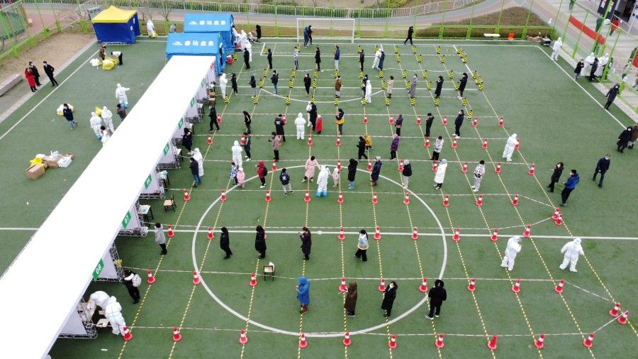 An aerial view shows people lining up at a nucleic acid testing site during the second round of mass testing for the coronavirus disease (Covid-19), after local cases of the Omicron variant were detected in Tianjin, China, 12 January 2022. (China Daily via Reuters)