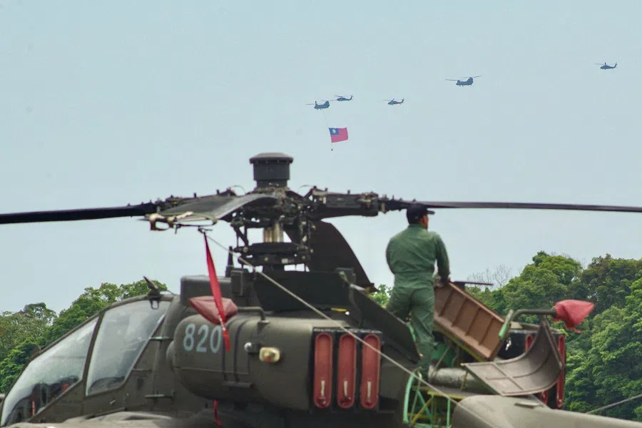 A Taiwanese serviceman maintains a US-made Apache attack helicopter as a US-made CH-47SD Chinook helicopter flies Taiwan’s flag past a military base in Taoyuan, Taiwan, on 7 May 2024. (Sam Yeh/AFP)