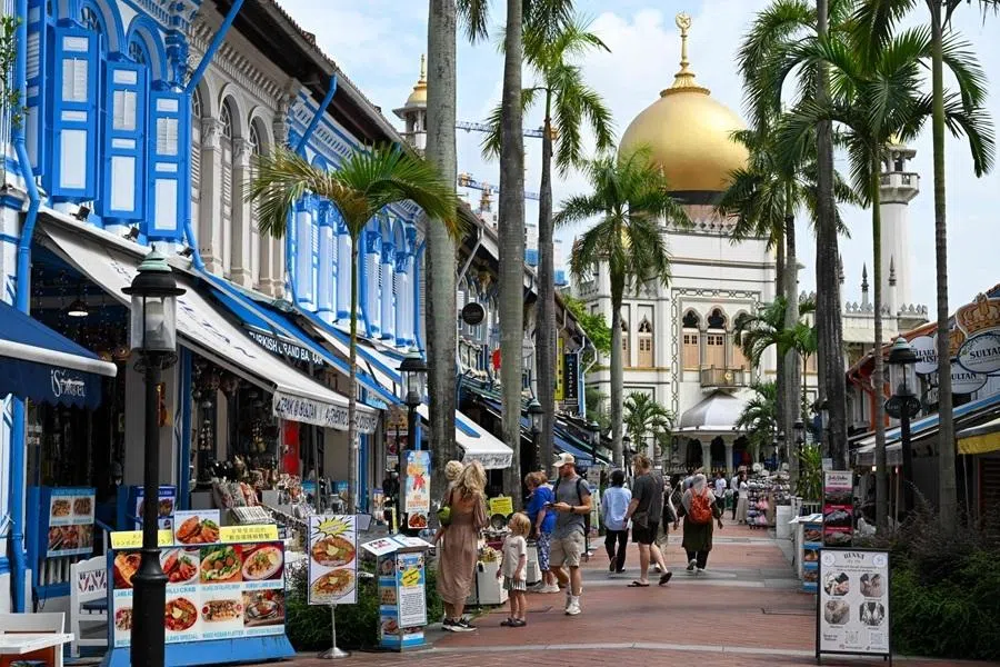People walk through an alley next to the Sultan Mosque in the Arab Street district of Singapore on June 16, 2026. (Photo by Roslan RAHMAN / AFP)