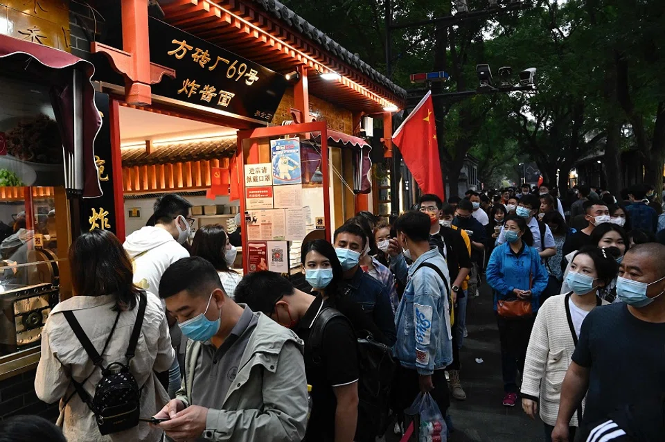 People walk in a commercial street during the country's national "Golden Week" holiday in Beijing, China, on 2 October 2021. (Jade Gao/AFP)
