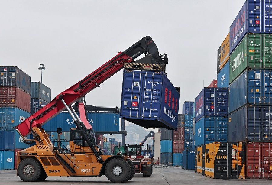 Workers move a shipping container at a commercial port in Vladivostok, Russia, 6 April 2023. (Tatiana Meel/Reuters)