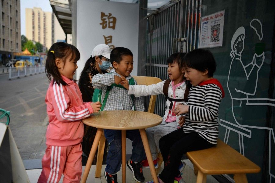 In this file photo taken on 11 May 2021 children play outside a cafe in Beijing. (Greg Baker/AFP)