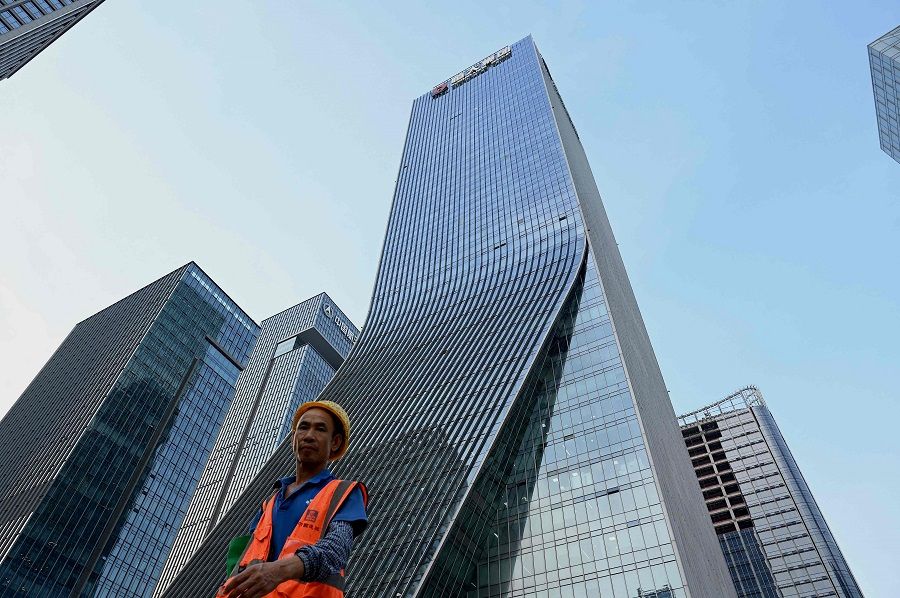 This file photo taken on 15 September 2021 shows a worker walking in front of the Evergrande headquarters in Shenzhen, Guangdong province, China. (Noel Celis/AFP)