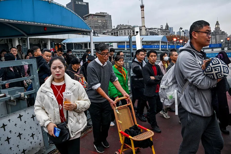 People board a ferry to cross the Huangpu River in Shanghai on 10 December 2023. (Hector Retamal/AFP)