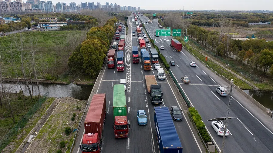 Freight trucks and other vehicles travel on a highway in this aerial photograph taken in Shanghai, China, on 25 March 2020. While much of the world's output is grinding to a halt because of the coronavirus, China is slowly emerging from its shutdowns by restarting production at factories and resuming some flights. (Qilai Shen/Bloomberg)