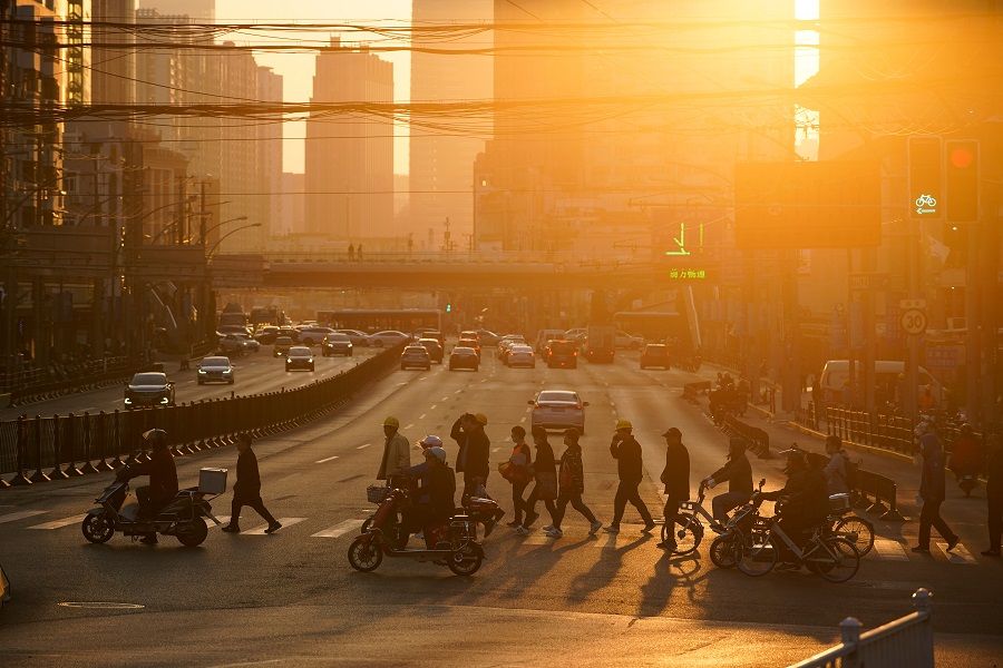People cross a street during sunset in Shanghai, China, 15 November 2021. (Aly Song/Reuters)