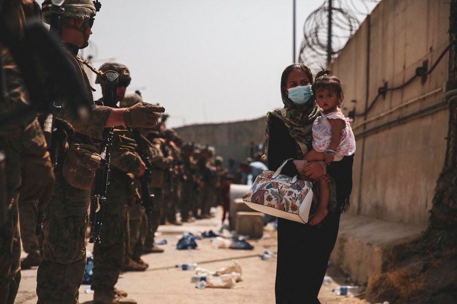 This handout photo courtesy of US Marines Corps shows Marines with the 24th Expeditionary Unit (MEU) guiding an evacuee during an evacuation at Hamid Karzai International Airport, Kabul, Afghanistan, 18 August 2021. (Sgt. Isaiah Campbell/US Marine Corps/AFP)