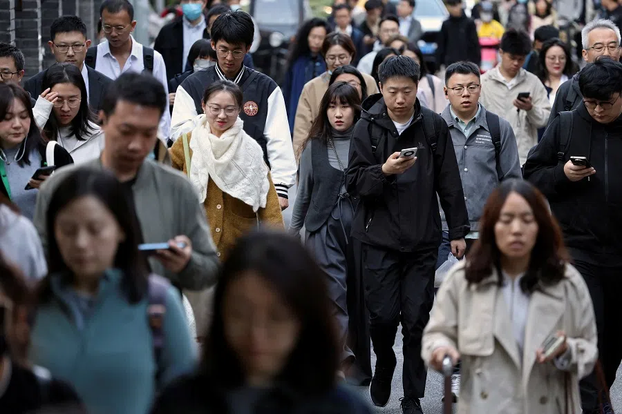 People walk along a street during morning rush hour near the Financial Street in Beijing, China, 8 October 2024. (Florence Lo/Reuters)