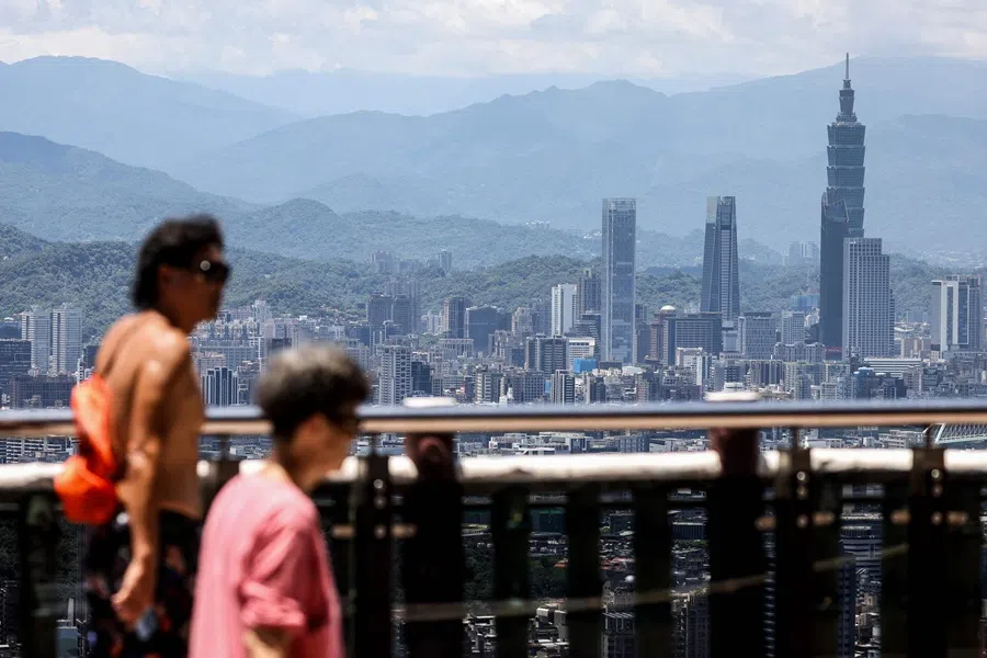People walk at a local temple with the background of the Taipei 101 building among residential and commercial buildings in Taipei on 10 June 2025. (I-Hwa Cheng/AFP)