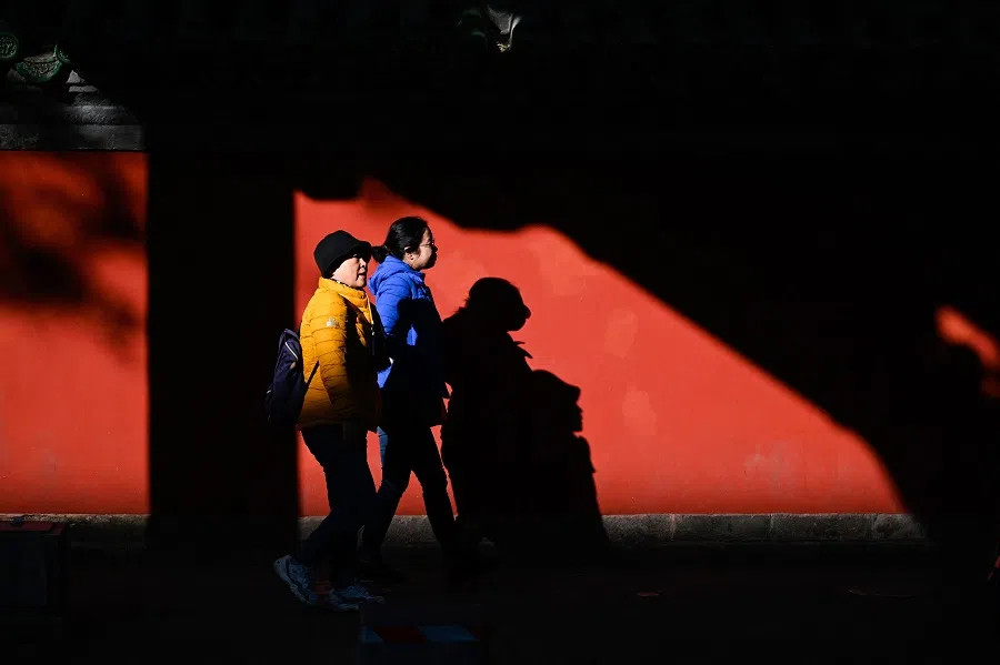 People walk down a street in Beijing, China, on 14 November 2023. (Wang Zhao/AFP)