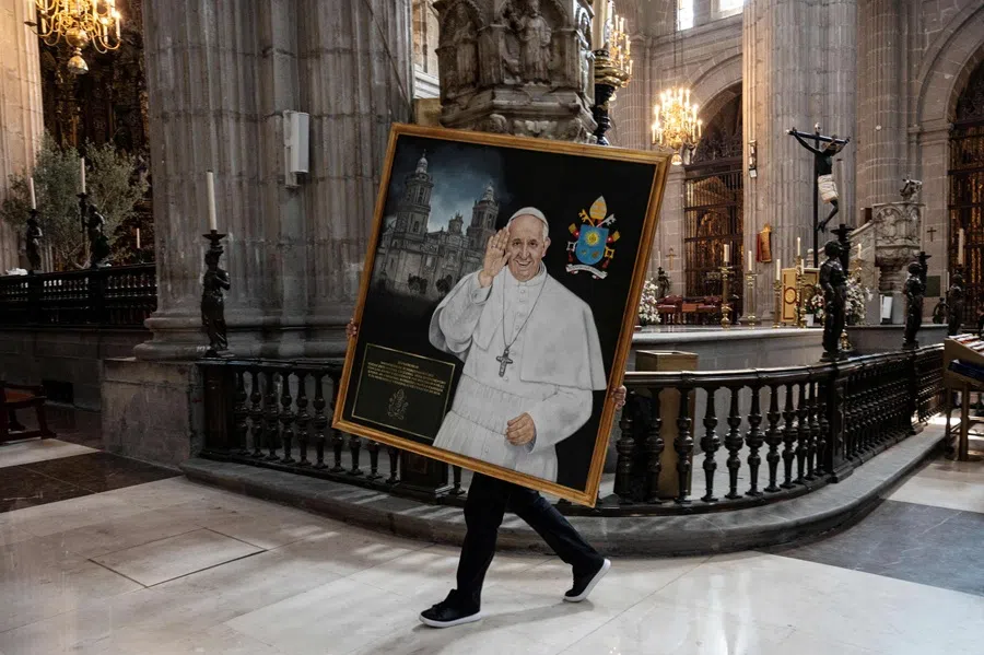 A church worker carries a portrait of the late Pope Francis during a memorial mass at the main cathedral at the El Zocalo Square in Mexico City on 21 April 2025. (Yuri Cortez/AFP)