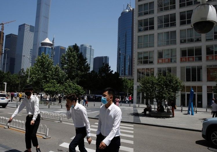 People wearing face masks walk past a street near an office and commercial complex in Beijing's central business district, on 2 June 2020. (Tingshu Wang/Reuters)