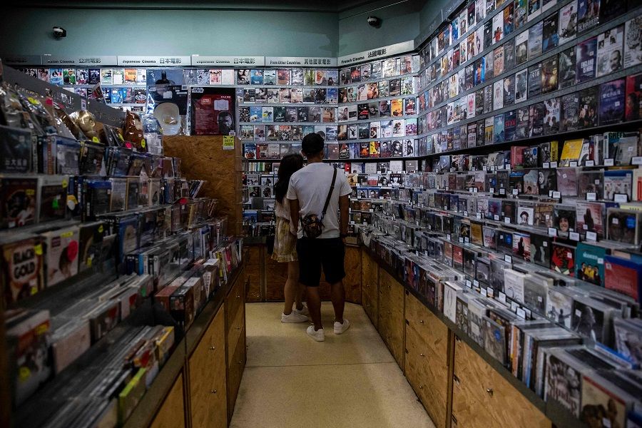 This picture taken on 2 September 2021 shows customers looking at movies for sale at a store inside a cinema in Hong Kong. (Isaac Lawrence/AFP)