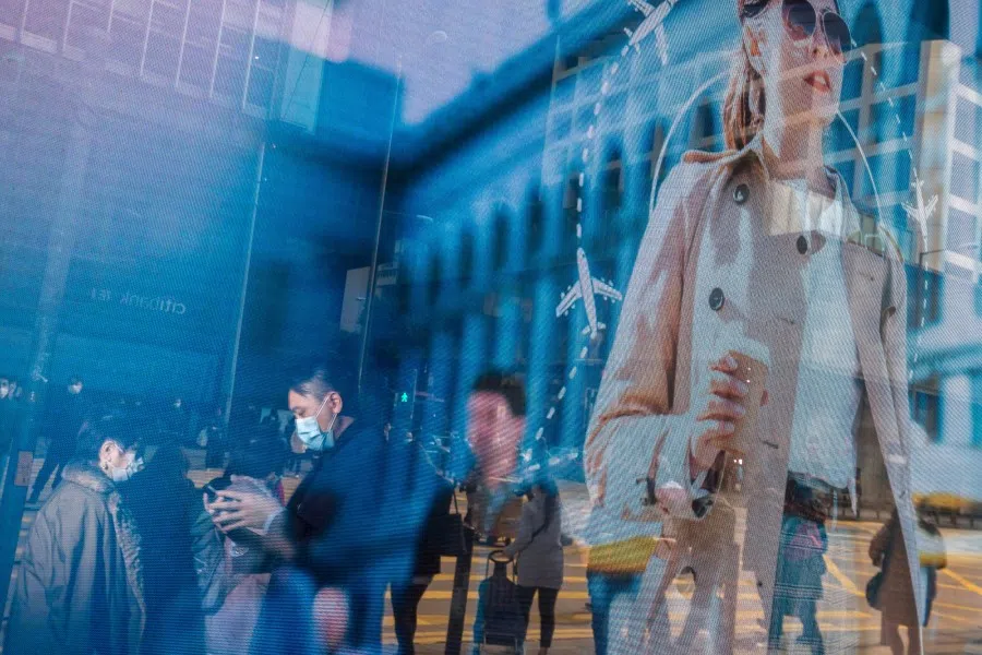 Pedestrians wearing protective masks are reflected in an advertisement in the Central district of Hong Kong, January 29, 2020. (Paul Yeung/Bloomberg)