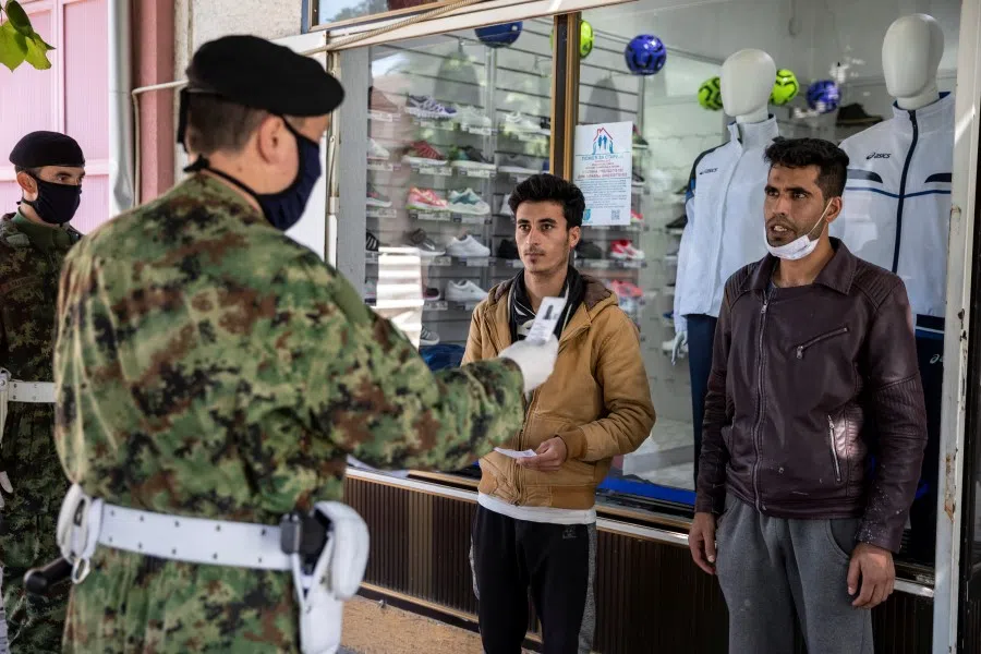 Serbian army soldiers check migrant's documents near the Sid-Point camp for migrants in Sid, Serbia, 21 May 2020. (Marko Djurica/REUTERS)