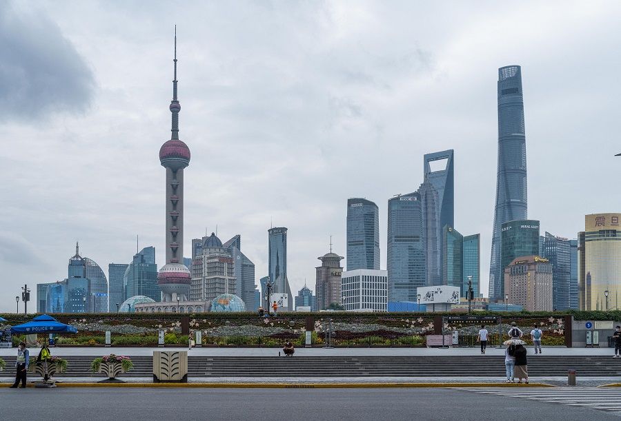 Pedestrians walk on the Bund, opposite Lujiazui Financial Center in Shanghai, China, on 10 June 2022. (Liu Jin/AFP)
