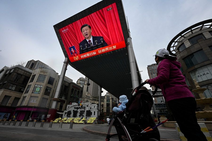 An outdoor screen shows a live news coverage of China's President Xi Jinping delivering a speech during the closing session of the National People's Congress (NPC) at the Great Hall of the People, along a street in Beijing, China, on 13 March 2023. (Jade Gao/AFP)