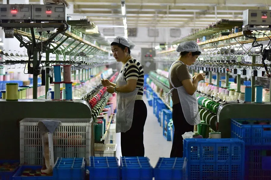 Workers check machines at a factory which produces silk cloth in Fuyang, Anhui province, China, on 16 April 2025. (AFP)
