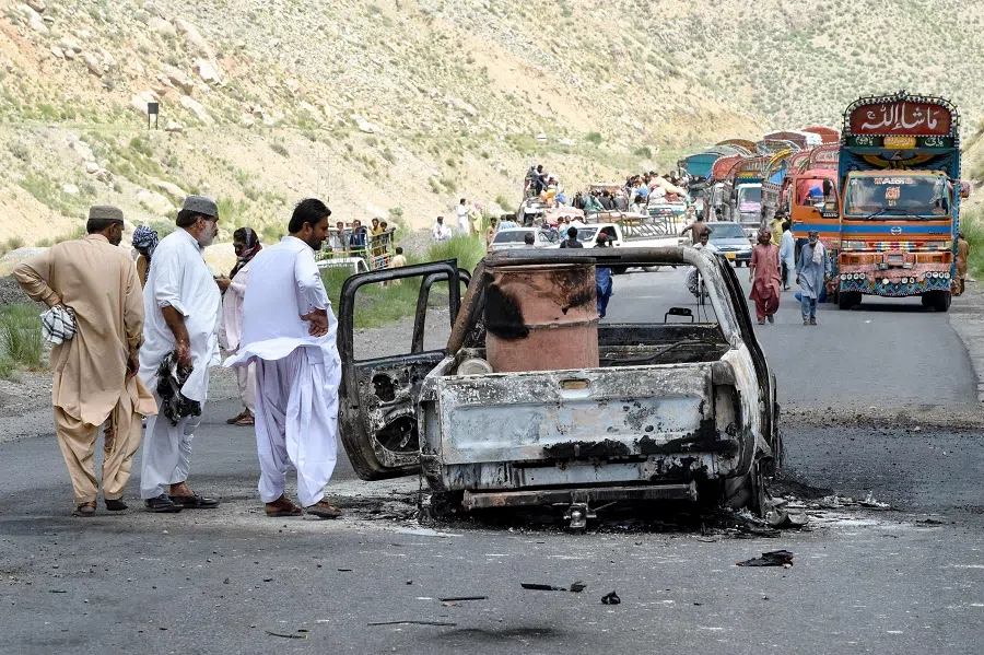 People look at a charred vehicle near a collapsed railway bridge the morning after a blast by separatist militants at Kolpur in Bolan district, Balochistan province on 27 August 2024.
