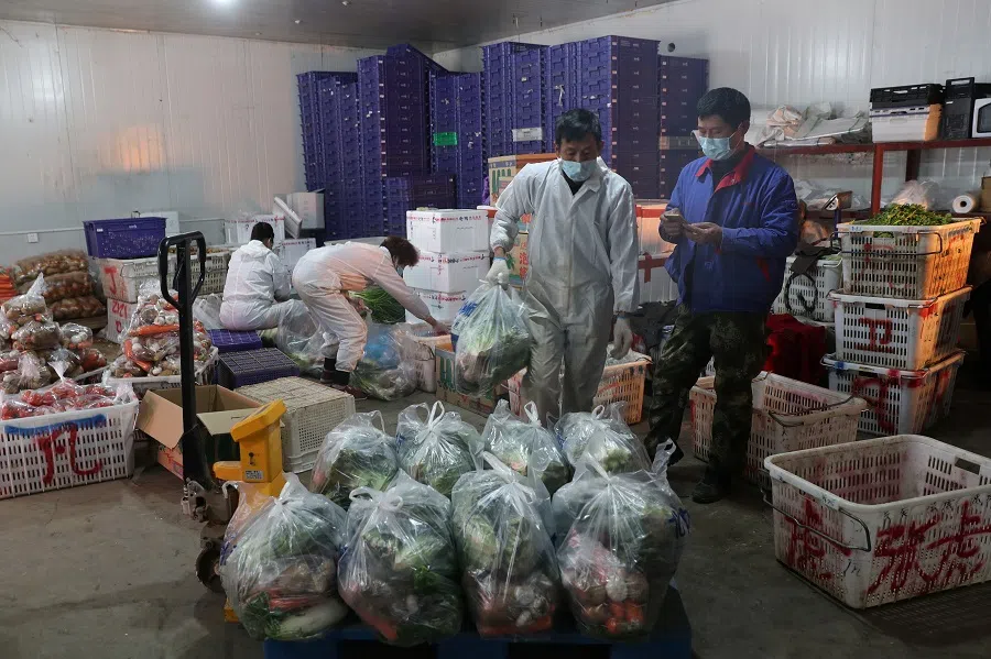 Workers wearing face masks pack vegetables at Baishazhou market in Wuhan, the epicentre of the Covid-19 outbreak, in Hubei province, China on 19 February 2020. (China Daily via Reuters)