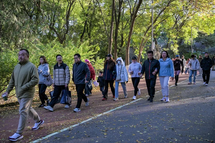 People walk across the Olympic Forest Park in Beijing on 26 October 2025. (Adek Berry/AFP)