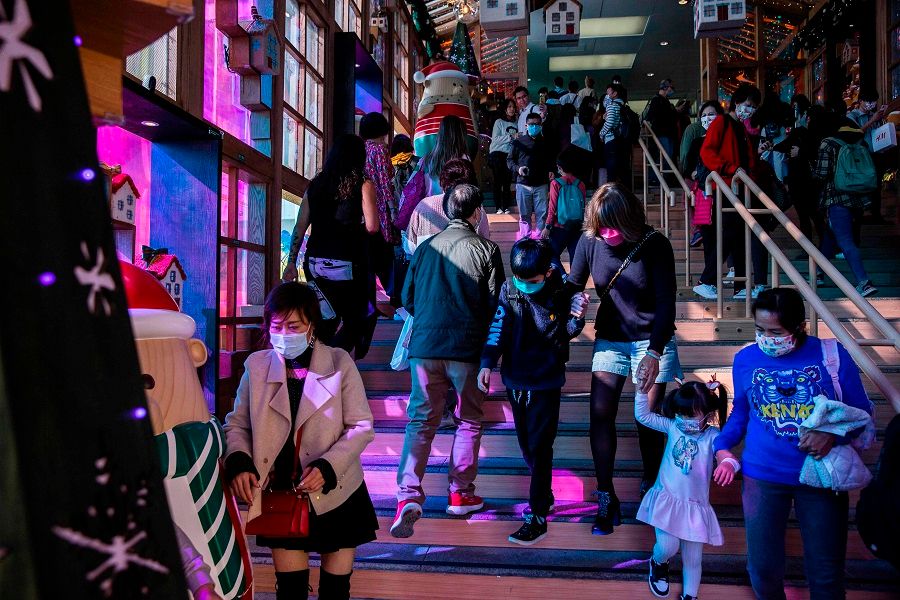 People wearing face maskswalk through a Christmas display inside a shopping mall in the Kowloon district of Hong Kong on 24 December 2020. (Isaac Lawrence/AFP)