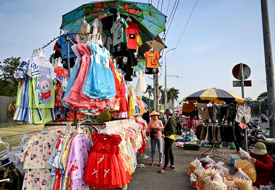 This photo taken on 23 December 2024 shows a worker (centre) shopping for clothes at a street market in Ho Chi Minh City, Vietnam. (Nhac Nguyen/AFP)