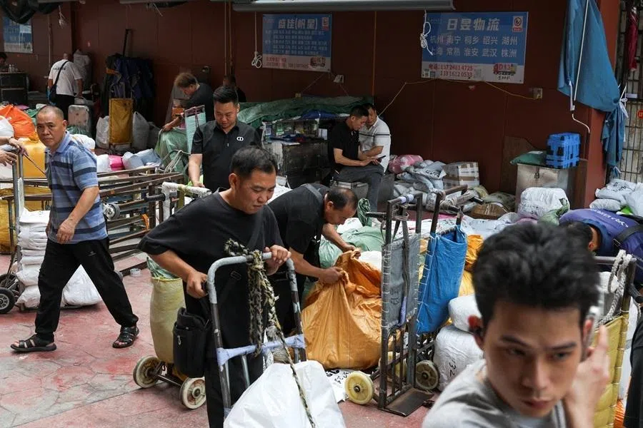 Logistics workers operate along a street in a clothing wholesale district in Guangzhou, Guangdong province, China, on 15 April 2026.