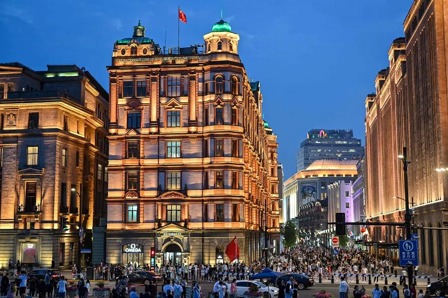 This photo taken on 25 May 2021 shows people walking along the Bund in Shanghai, China. (Hector Retamal/AFP)