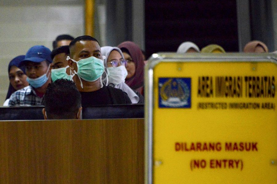 Passengers wearing facemasks to help stop the spread of a deadly virus which began in the Chinese city of Wuhan, pass through immigration upon arrival at the Sultan Iskandar Muda International Airport in Blang Bintang, Aceh Besar, on 27 January 2020. (Chaideer Mahyuddin/AFP)