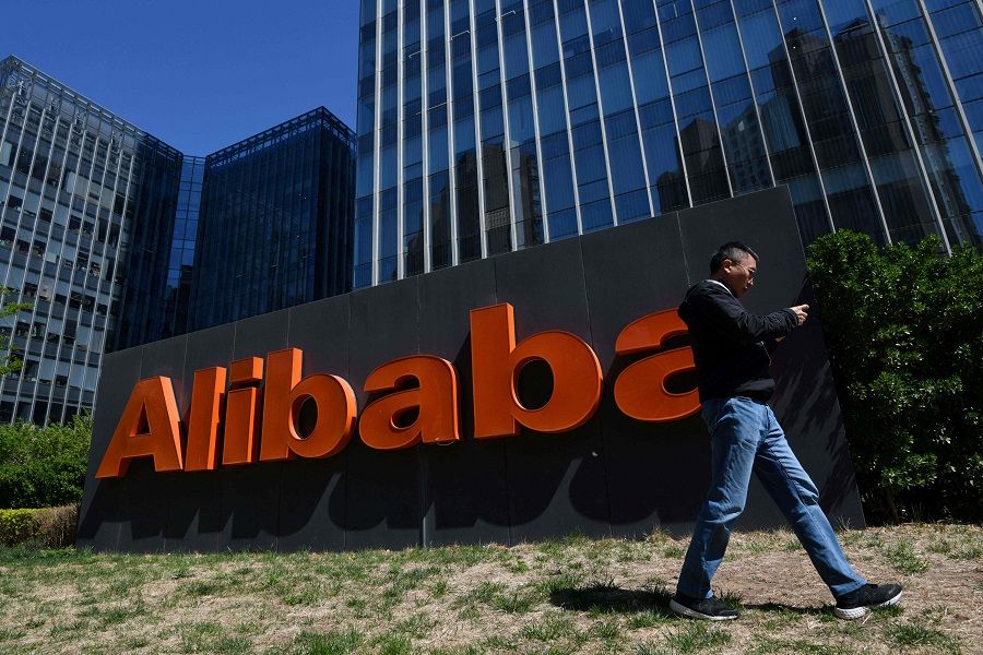 In this file photo taken on 13 April 2021, a man walks past an Alibaba sign outside the company's office in Beijing, China. (Greg Baker/AFP)