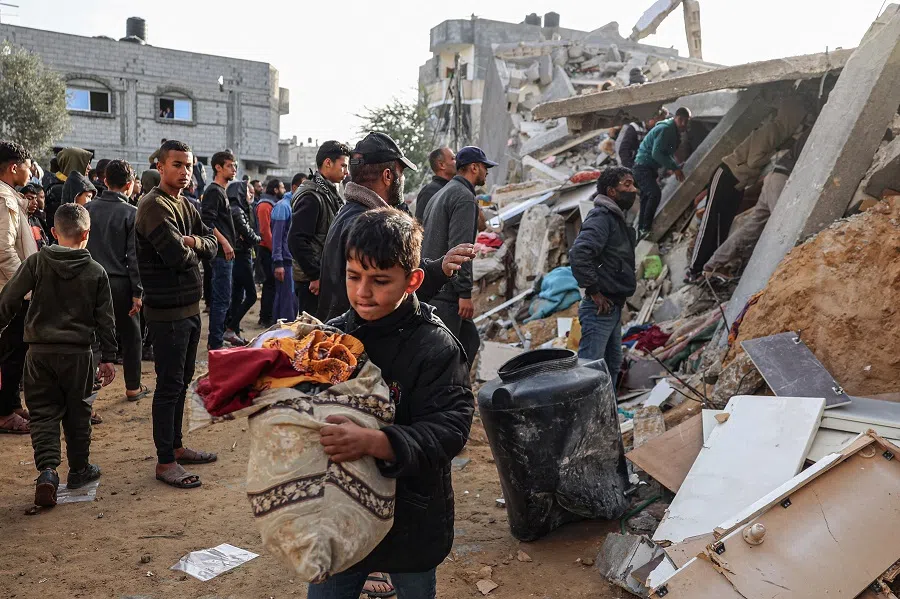 A Palestinian child carries away items salvaged from the rubble of a house destroyed in an overnight Israeli air strike in Rafah in the southern Gaza Strip on 3 March 2024. (Said Khatib/AFP)