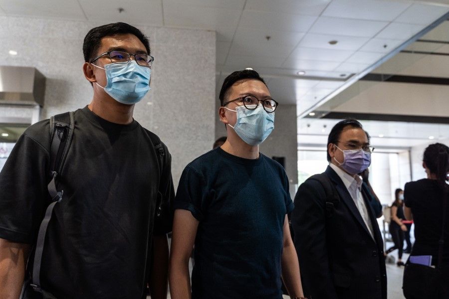 Former pro-democracy district councilors Sze Tak-loy (left) and Jonathan Ho Kai-ming (centre) arrive at the West Kowloon Magistrates' Courts for a hearing in Hong Kong, 8 July 2021. Pro-democracy activists are being prosecuted over their roles in helping organise a primary that drew more than 600,000 voters in July last year to choose candidates for LegCo elections that were later postponed. (Chan Long Hei/Bloomberg)