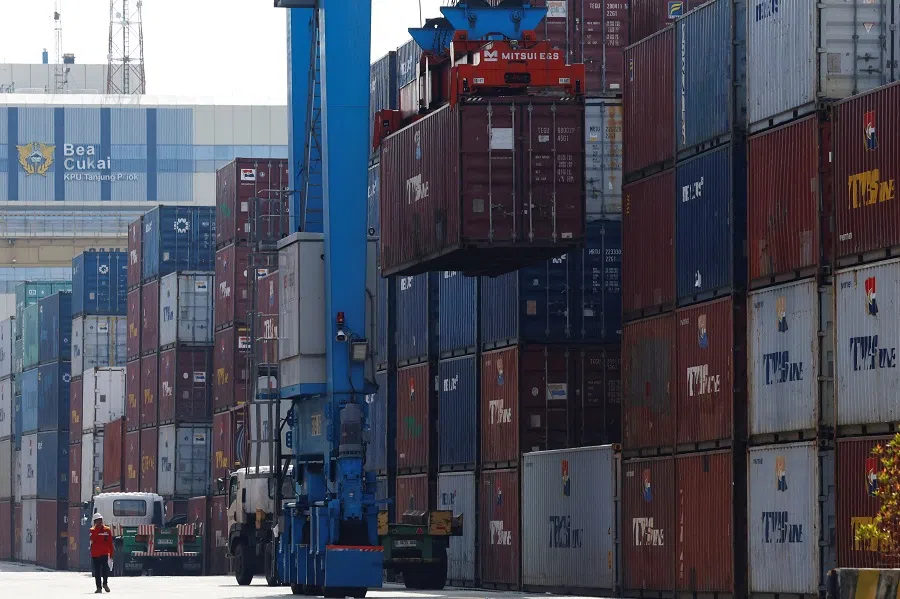 A man walks past as a container is unloaded from a truck at Tanjung Priok Port in Jakarta, Indonesia, on 3 April 2025. (Ajeng Dinar Ulfiana/Reuters)