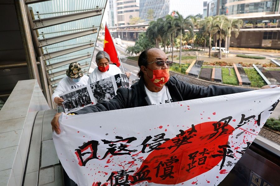 Protesters from a pro-China group carry banners and Chinese and Japanese national flags during a protest on the anniversary of the Nanjing Massacre, near Japan's consulate in Hong Kong, China, 13 December 2021. (Tyrone Siu/Reuters)