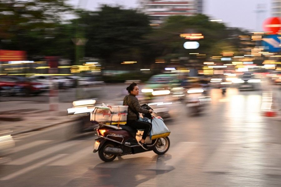 A woman rides her scooter against the traffic along a street in Hanoi on 23 March 2021. (Manan Vatsyayana/AFP)