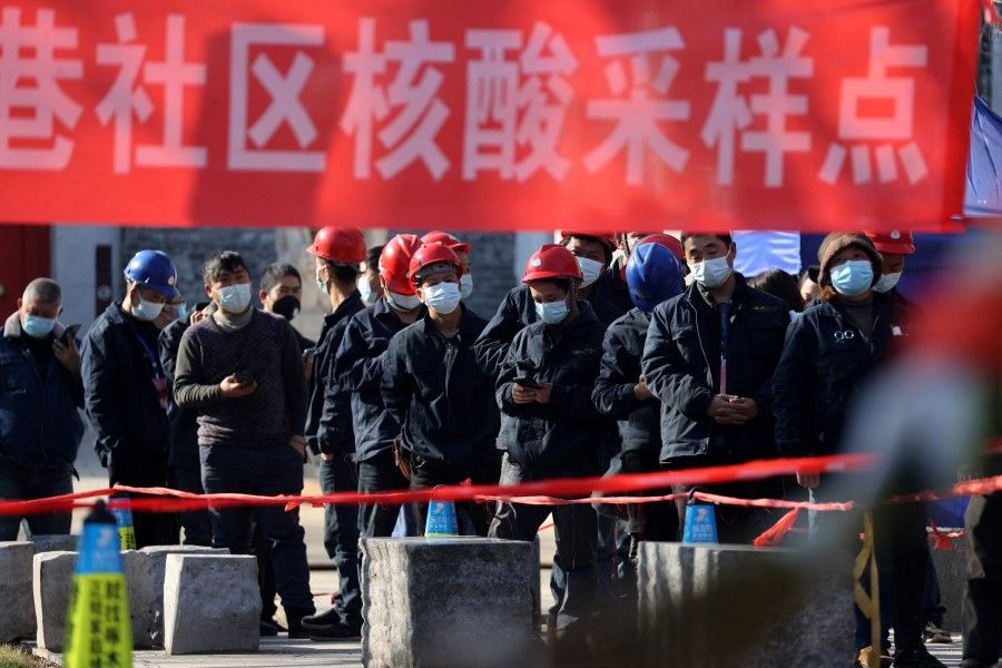 Construction workers line up to be tested for Covid-19 in Xi'an in China's northern Shaanxi province on 21 December 2021. (AFP)