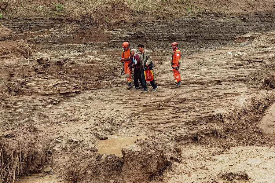This photo taken on 16 July 2022 shows rescue workers evacuating residents after flooding in Qingyang, Gansu province, China. (AFP)