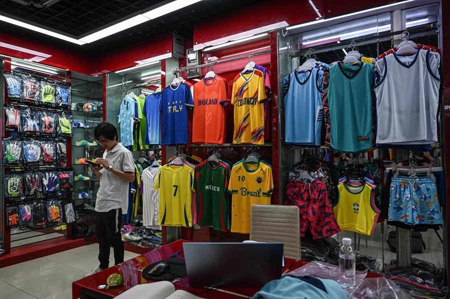 A vendor checks his phone at a sporting goods store at the Yiwu International Trade Market in Yiwu, in eastern China’s Zhejiang province on 17 September 2025. (Jade Gao/AFP)