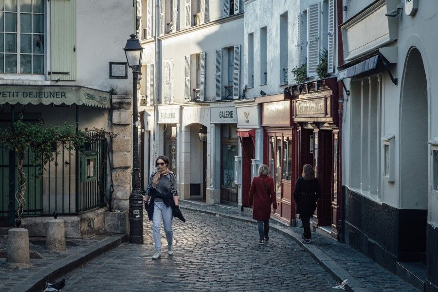 A pedestrian uses a headscarf to protect herself against infection as she walks past closed cafes and retail outlets during coronavirus lockdown measures in the Montmartre district of Paris, France, April 14, 2020. (Cyril Marcilhacy/Bloomberg)