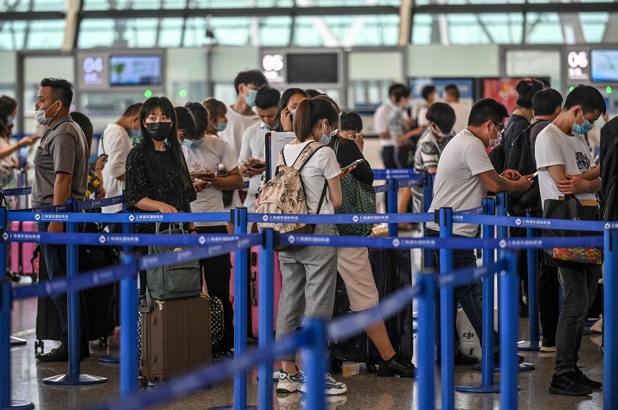 Passengers wait in line at the counter area following preventive procedures against the Covid-19 coronavirus in Pudong International Airport in Shanghai on 11 June 2020. (Hector Retamal/AFP)