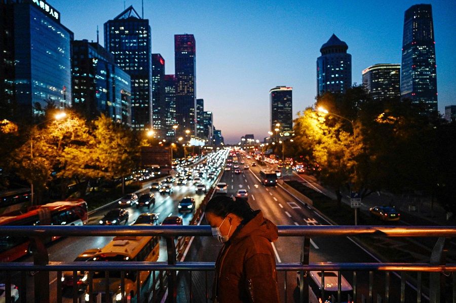 A woman walks on an overpass at the central business district in Beijing on 14 November 2023. (Jade Gao/AFP)
